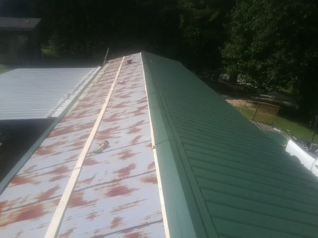 Old rusted panels beside newly installed green metal roofing — Wind Damage Roof Repair by Roofing Brothers in Denmark